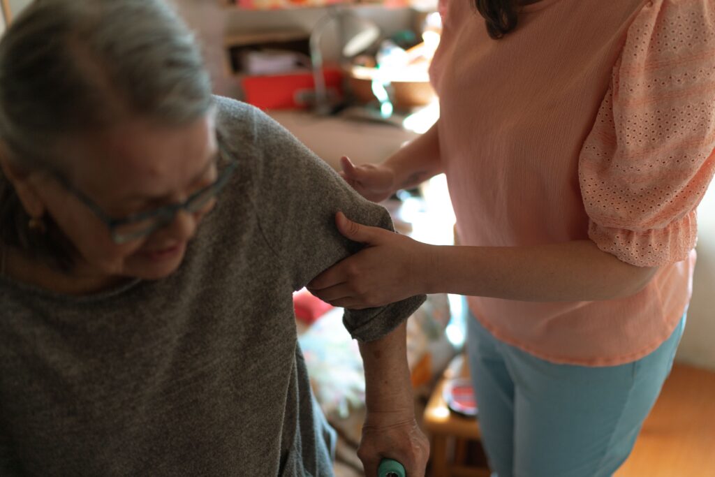 Professional caregiver assisting an older adult with daily living activities at home.